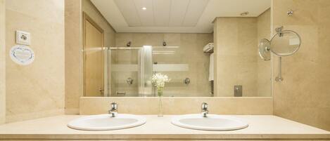 A modern bathroom with two sinks, a glass shower enclosure, and a large mirror.