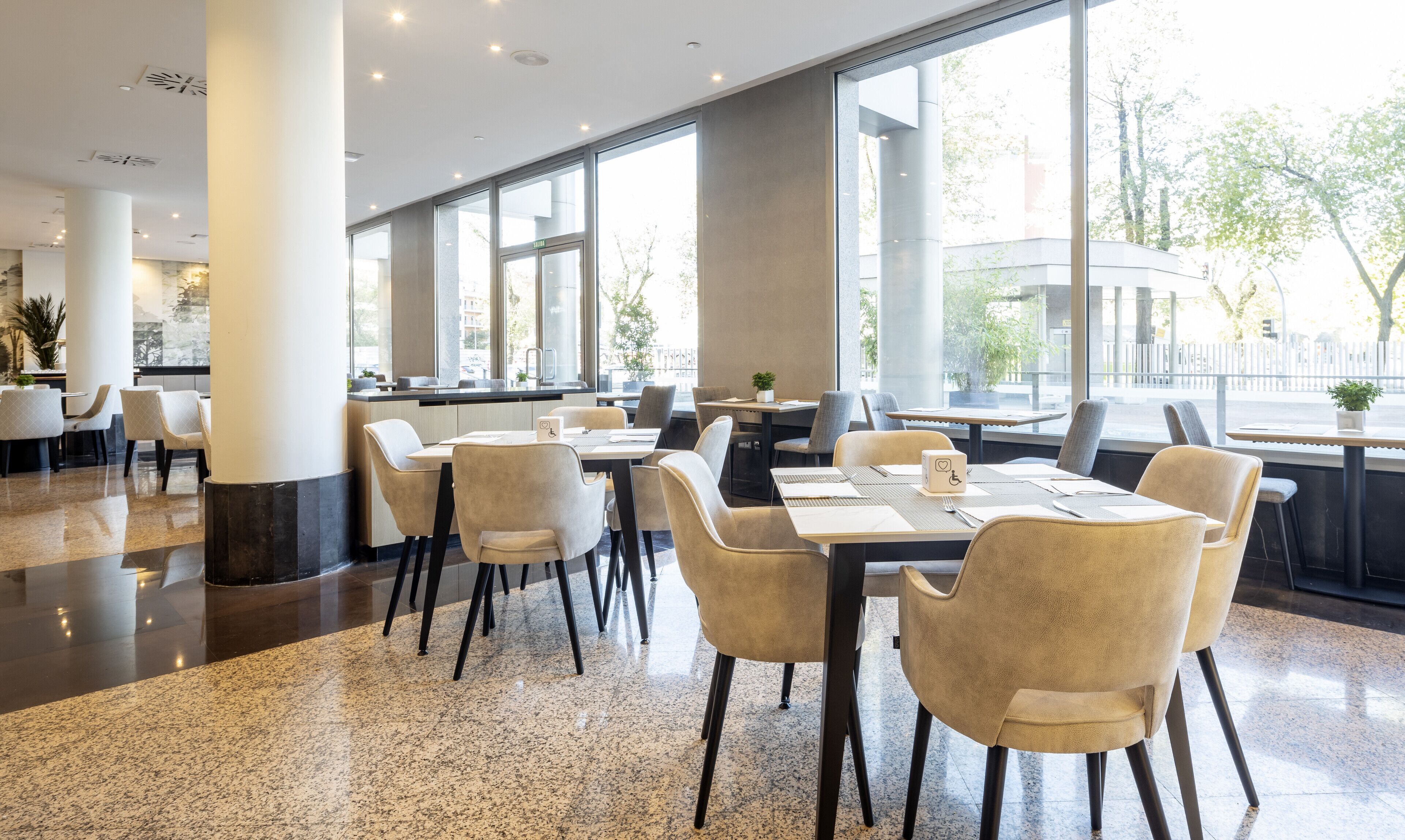 Un restaurante moderno con amplios ventanales, suelos de granito pulido y mobiliario contemporáneo.