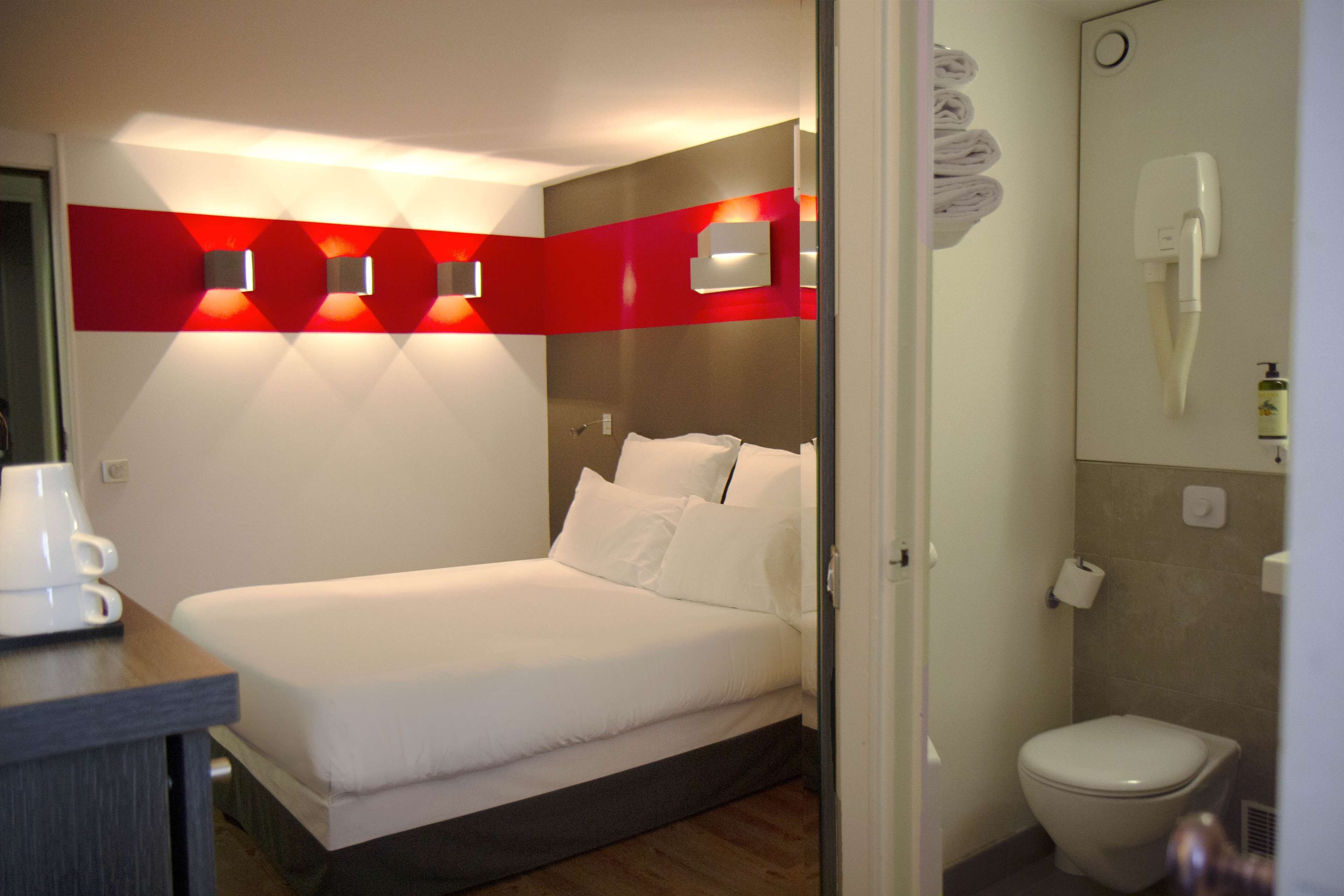 A hotel room with a bed, a coffee maker, a shower, and a toilet.