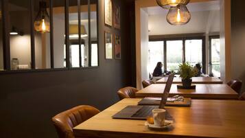 A modern conference room with leather chairs, a wooden table, a laptop, a cup, and a potted plant.