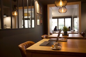 A modern conference room with leather chairs, a wooden table, a laptop, a cup, and a potted plant. - Best Western The Hotel Versailles (Buc)