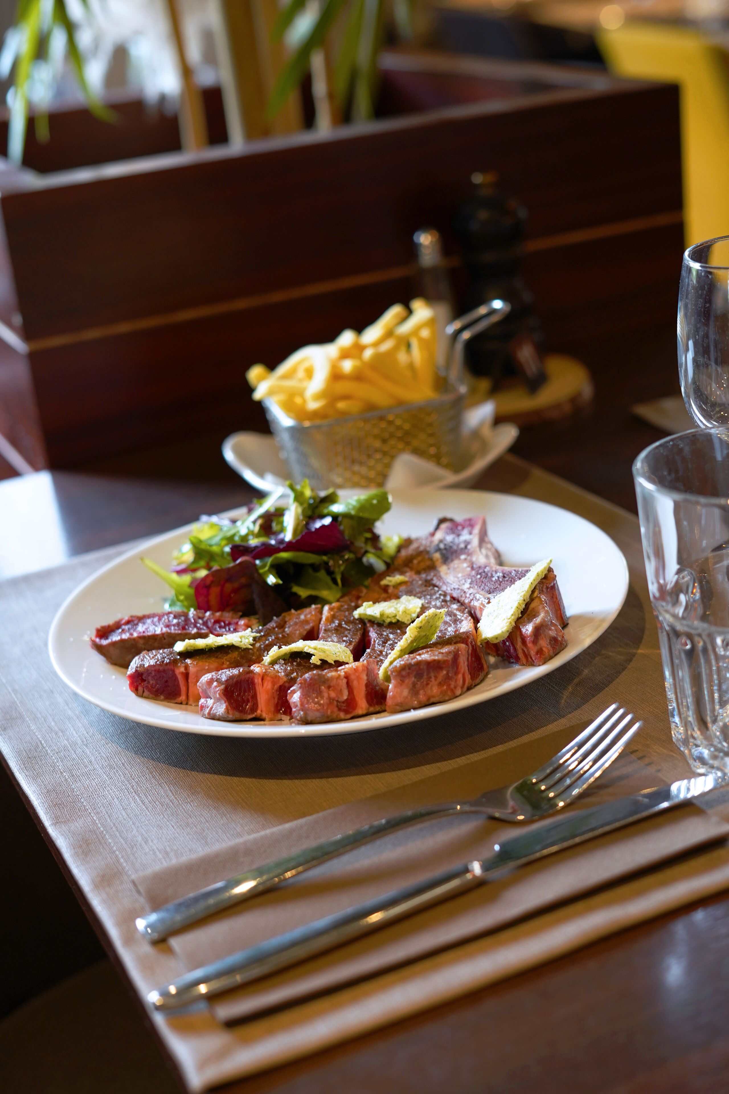 Un plato de carne con papas fritas y ensalada sobre una mesa.