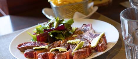 Un plato de carne con papas fritas y ensalada sobre una mesa.