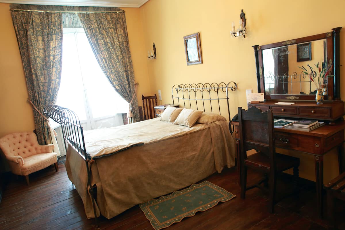 A bedroom with a bed, a desk, a chair, and a dresser.