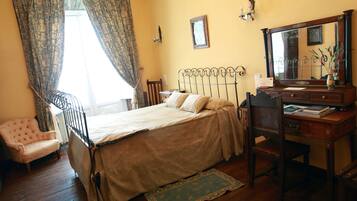 Een slaapkamer met een bed, bureau, stoel en dressoir.