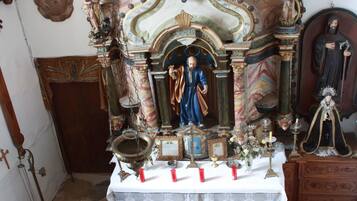 Un santuario religioso ornamentado con una estatua de un santo, un crucifijo y un icono religioso enmarcado.