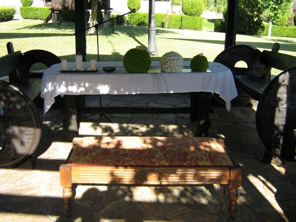 Un espace de restauration en plein air avec une table dressée pour deux personnes, un banc et un sol en pierre.