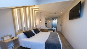 A modern hotel room with a large bed, bedside table, and a flat-screen TV mounted on the wall. - Hotel Fruela (Oviedo)