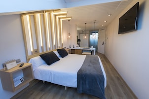 Una habitación de hotel moderna con una cama grande, una mesita de noche y un televisor de pantalla plana en la pared.