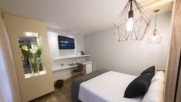 Habitació d'hotel moderna amb un llit, un escriptori, una televisió i una làmpada de suspensió geomètrica singular.