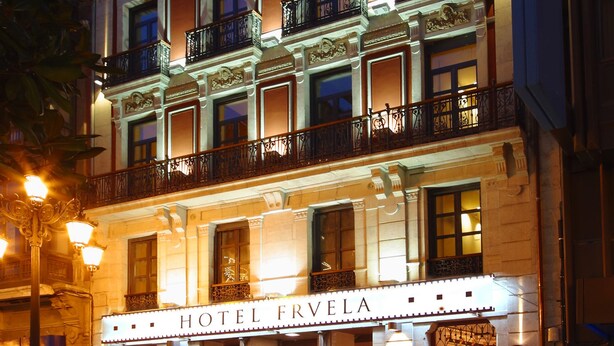 A multi-story hotel with a classic facade, balconies, and a well-lit entrance. - Hotel Fruela (Oviedo)
