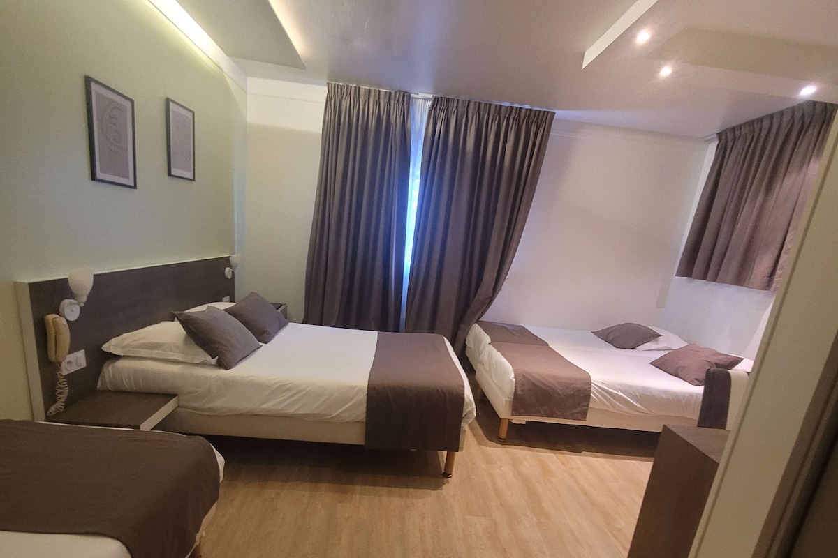 Habitación de hotel con dos camas, piso de madera y un amplio ventanal con cortinas.