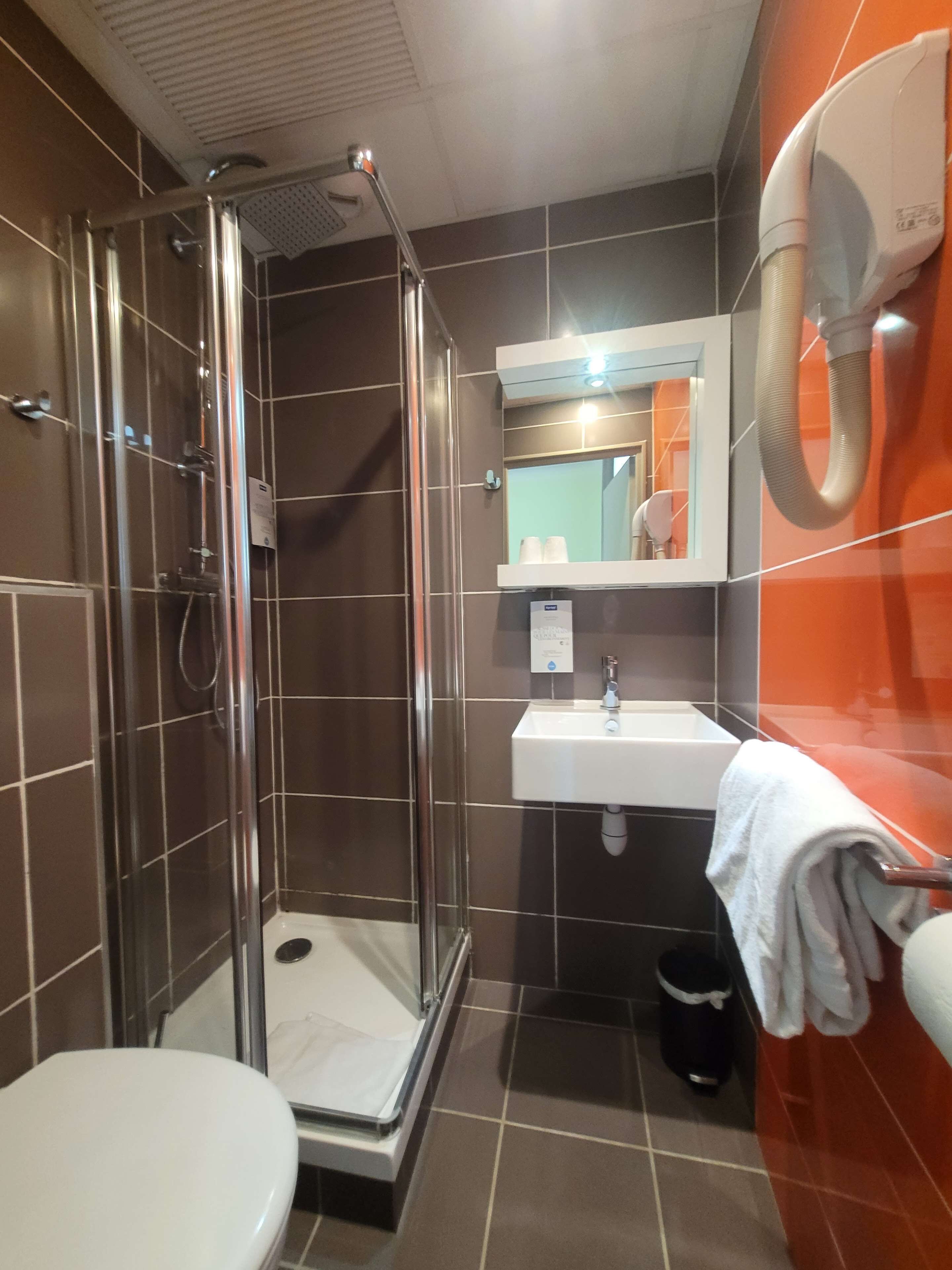Une salle de bain moderne avec une douche à parois de verre, un lavabo blanc et des toilettes.