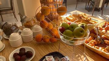 A breakfast buffet with fruits, pastries, and condiments.