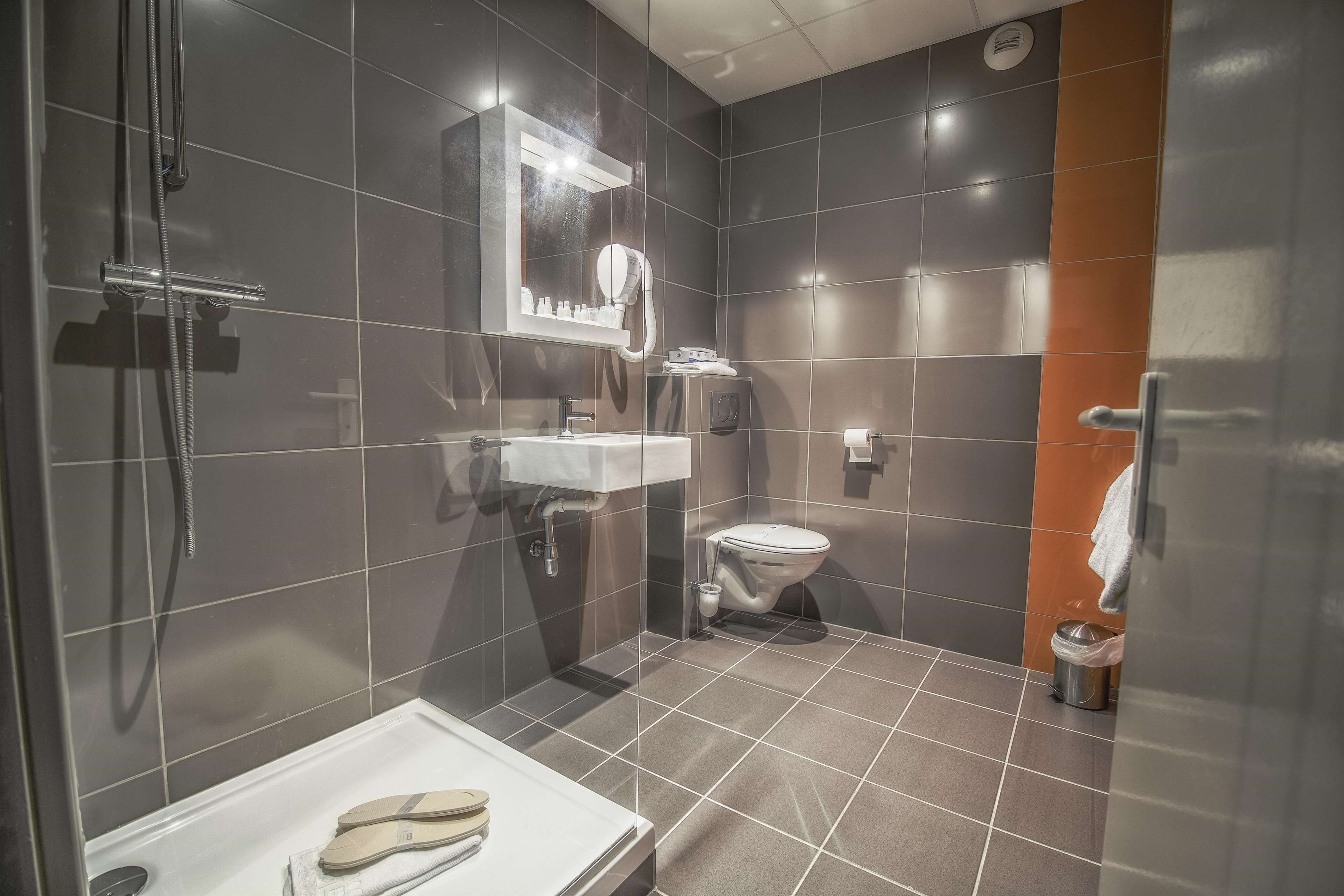 A modern bathroom with a shower, toilet, and sink.