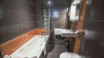 A modern bathroom with a bathtub, toilet, and sink.
