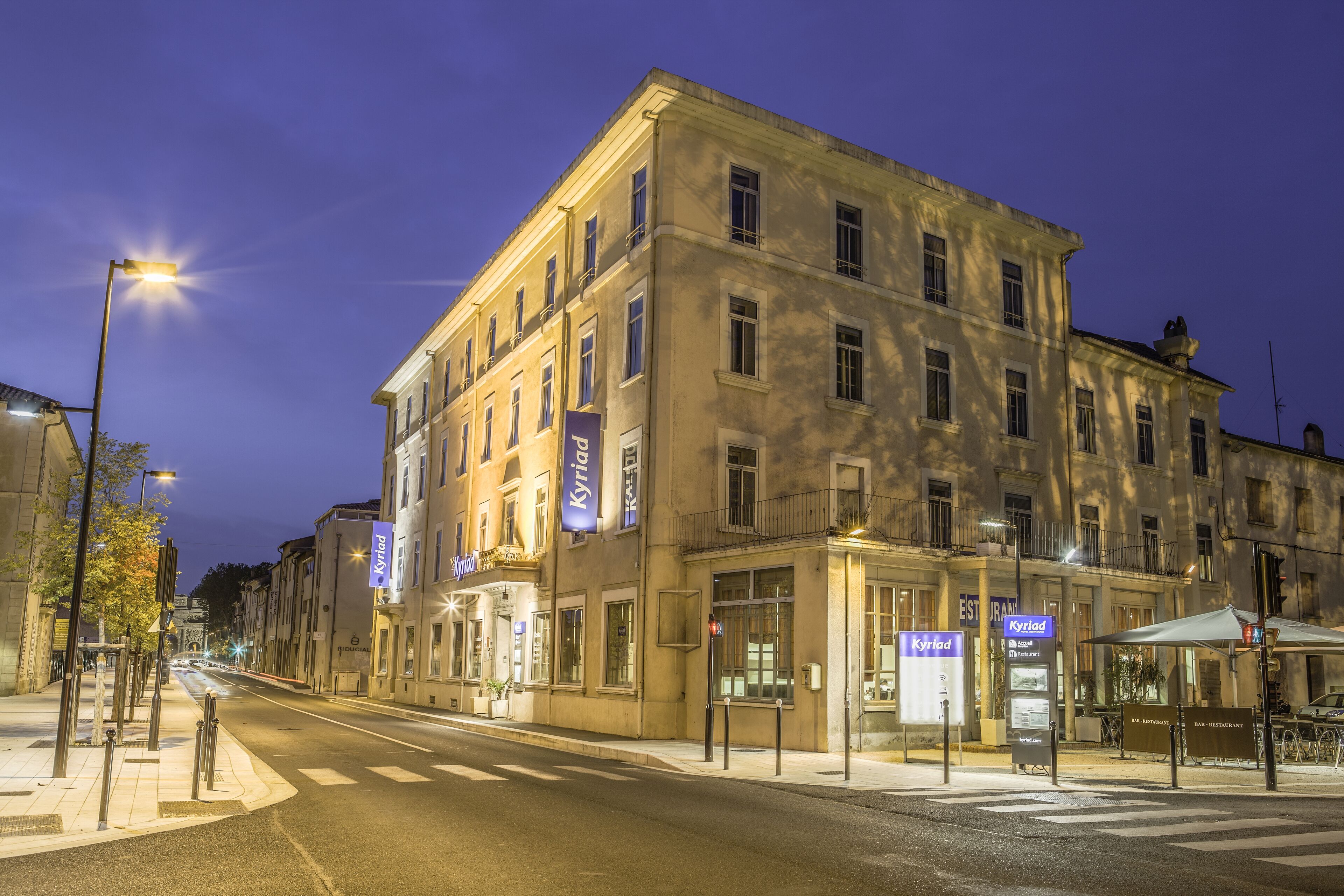 A multi-story building with signage for 'Kyriad' and 'Pillars'.