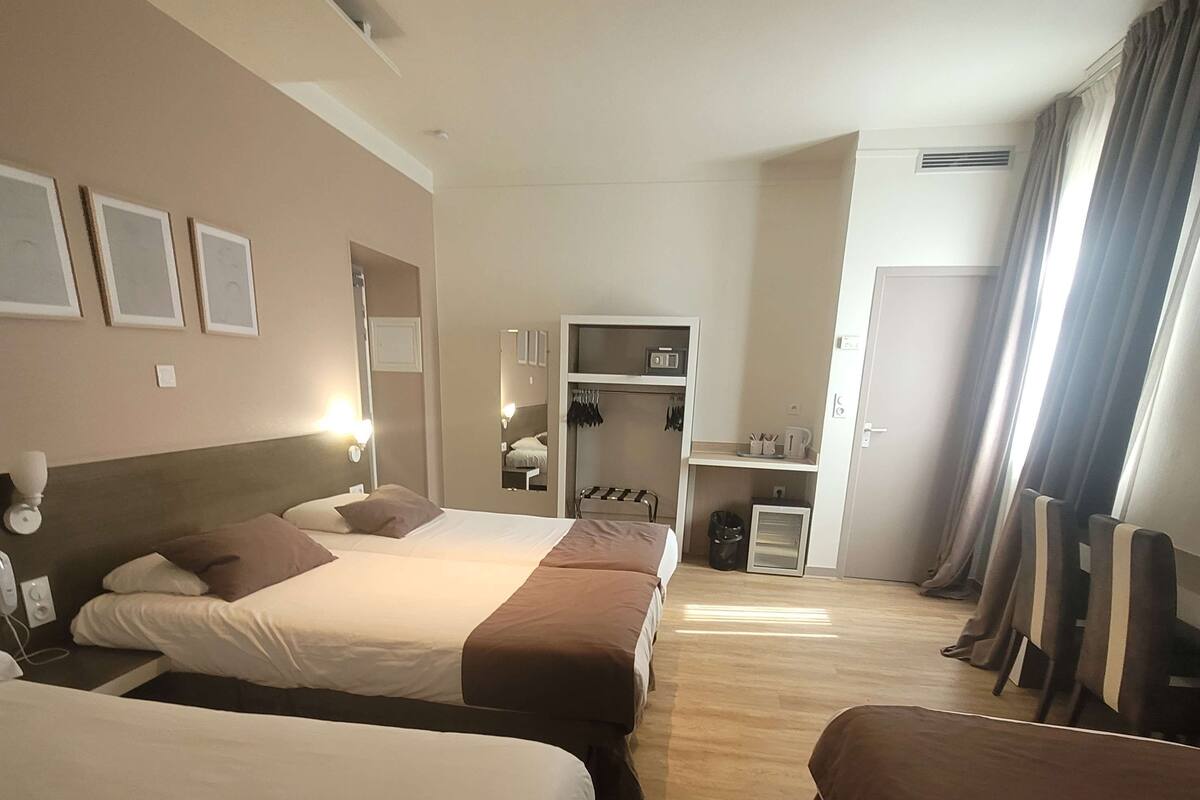 Una habitación de hotel con dos camas, un armario, un escritorio y un espejo.