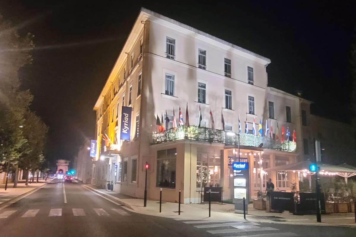 Un hotel con balcón, varias banderas y un cartel que dice "Kyriad".