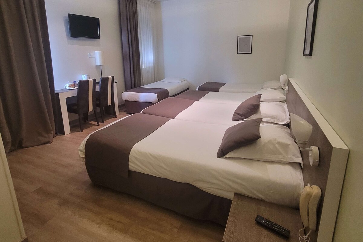 Una habitación de hotel con dos camas, un escritorio, una silla, un televisor y un teléfono.