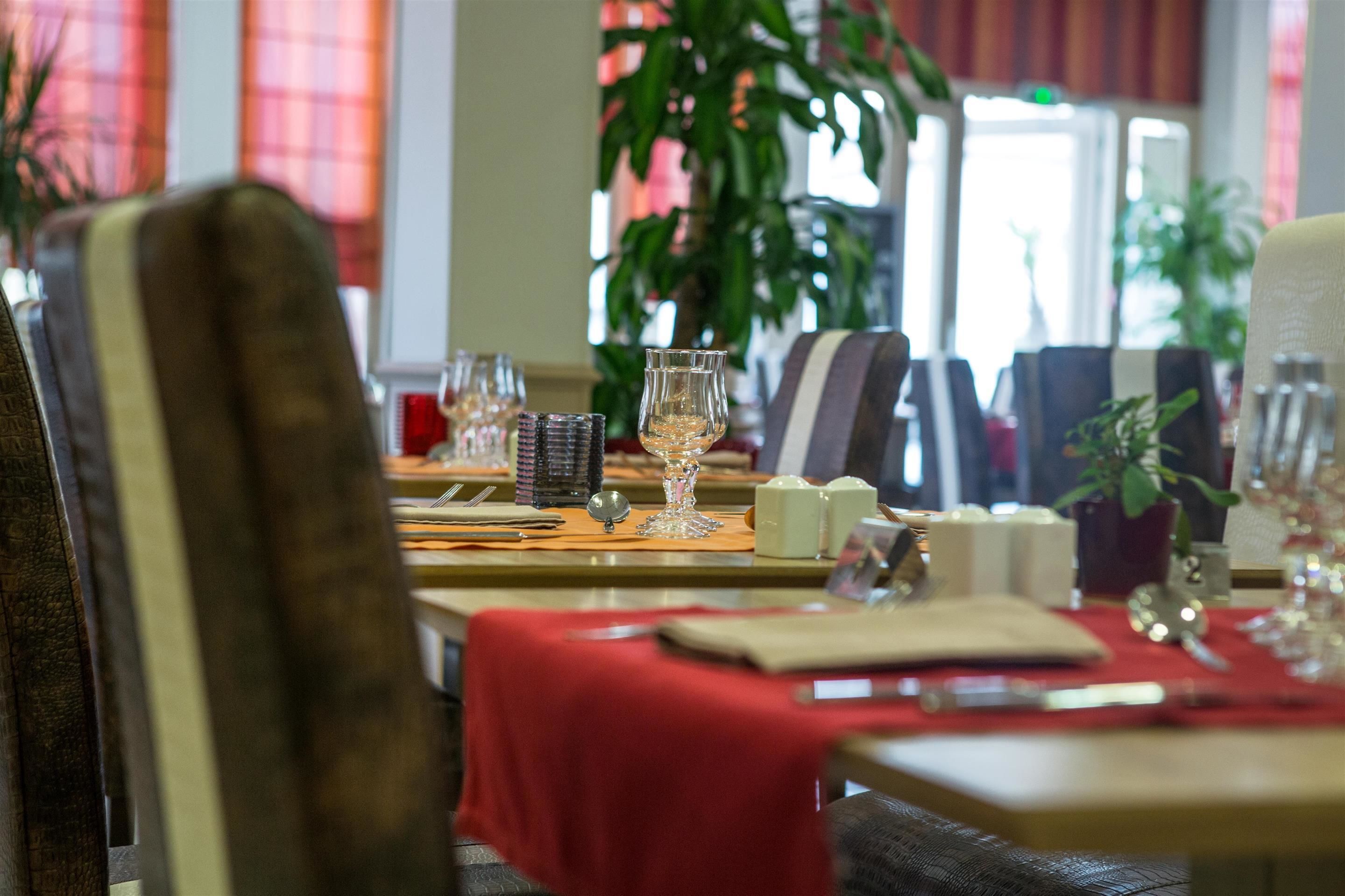A dining area with tables set for a meal, including wine glasses, plates, and cutlery.