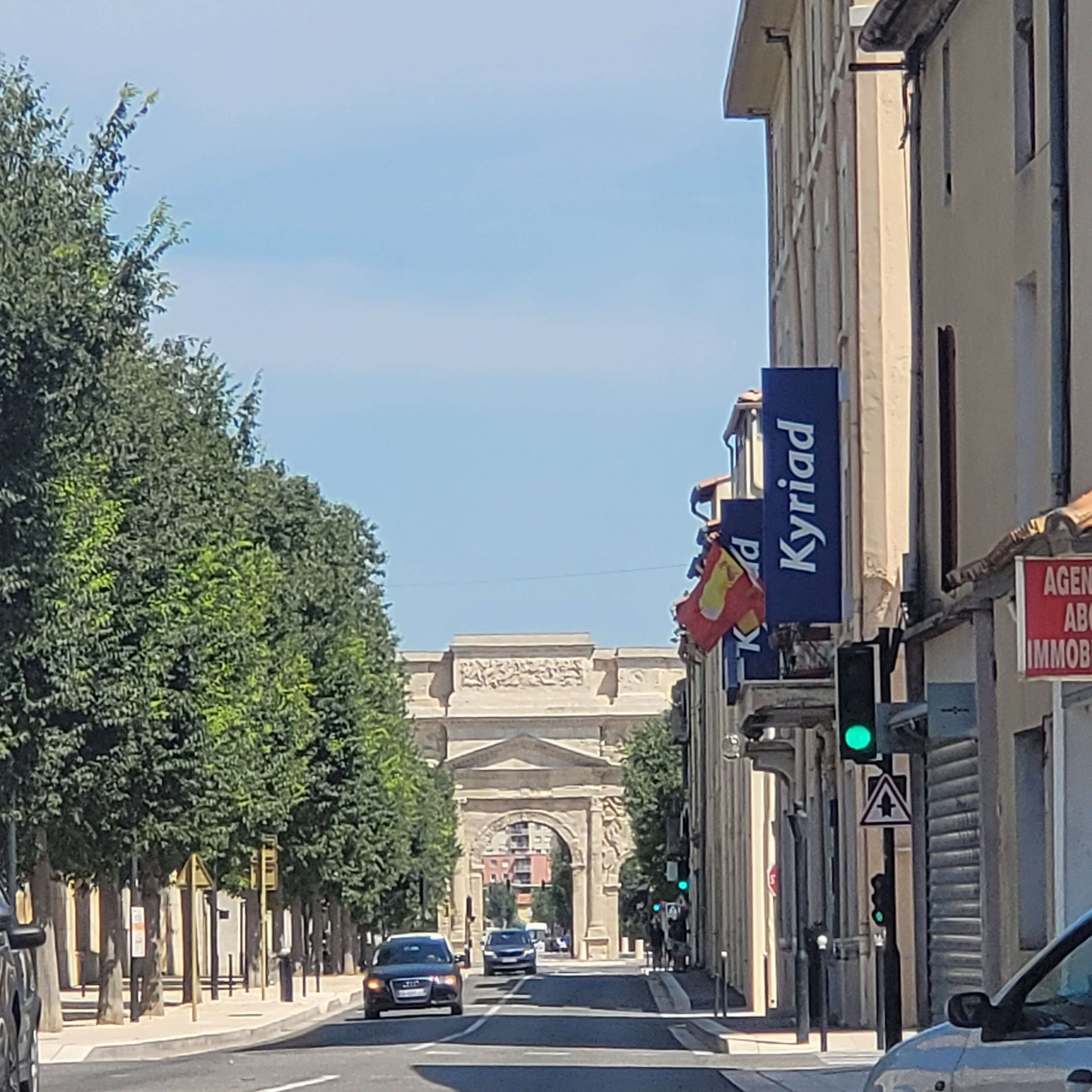 A street view with a building featuring a large archway in the background.