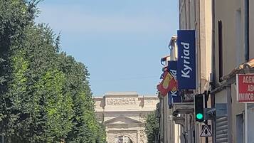 A street view with a building featuring a large archway in the background.