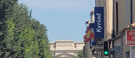 Vista de la calle con un edificio que destaca por un gran arco en el fondo.