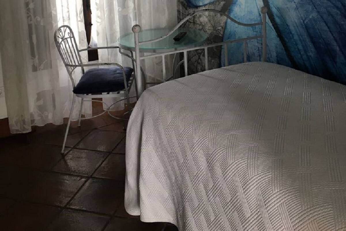 Une chambre avec un lit, une chaise, une petite table et une grande fresque représentant des papillons sur le mur.