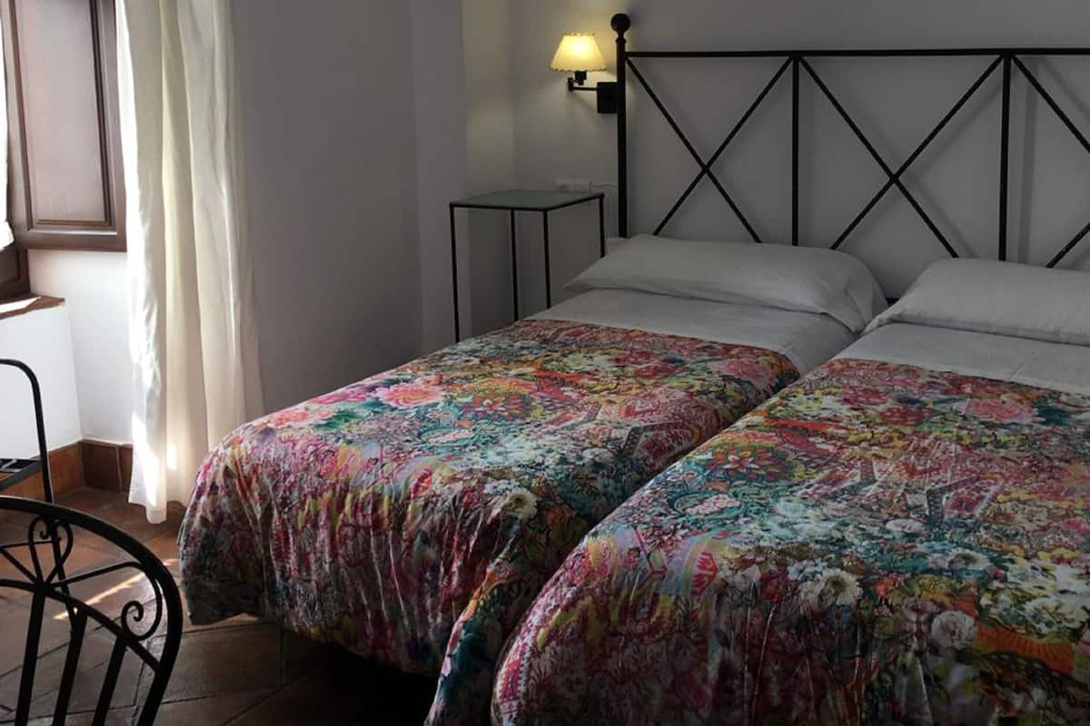 Une chambre avec deux lits, une table de chevet, une lampe et une chaise.