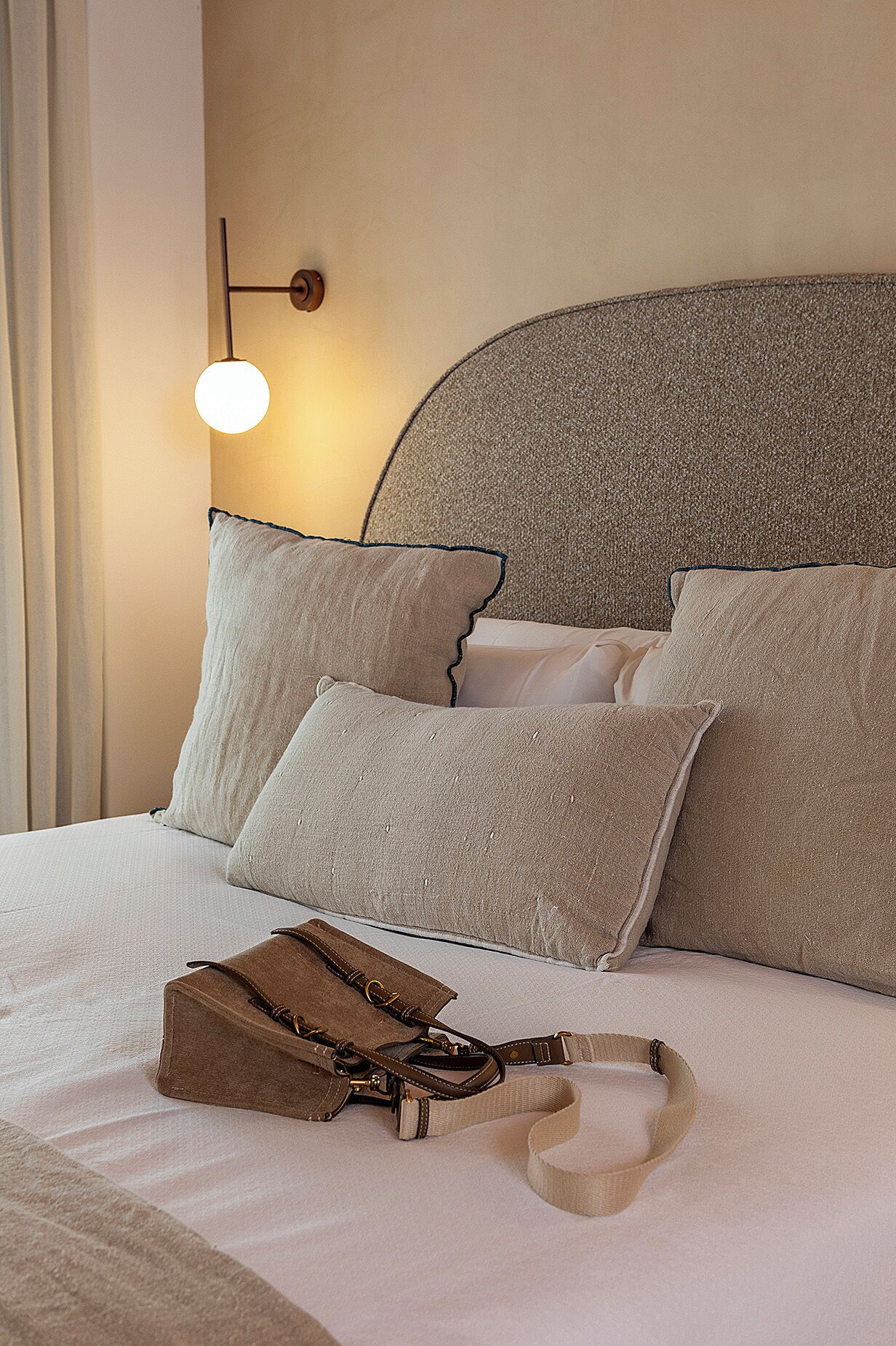A neatly made bed with pillows and a handbag on it.