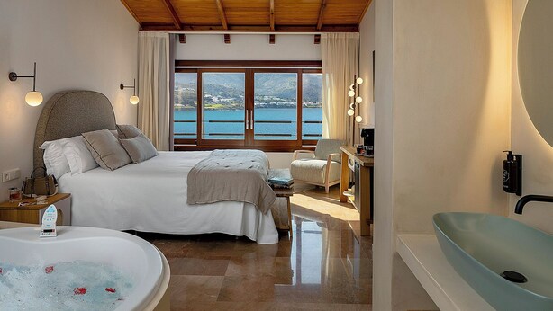 Une chambre avec un grand lit, une baignoire et une vue sur la mer.