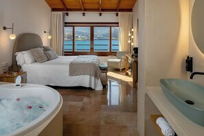 Ein Schlafzimmer mit einem großen Bett, einer Badewanne und Meerblick.