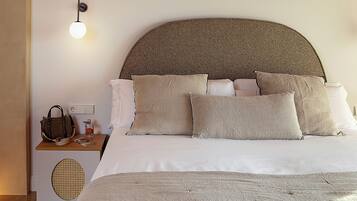 A neatly made bed with a large, textured headboard, a bedside table with a lamp, and a small speaker.