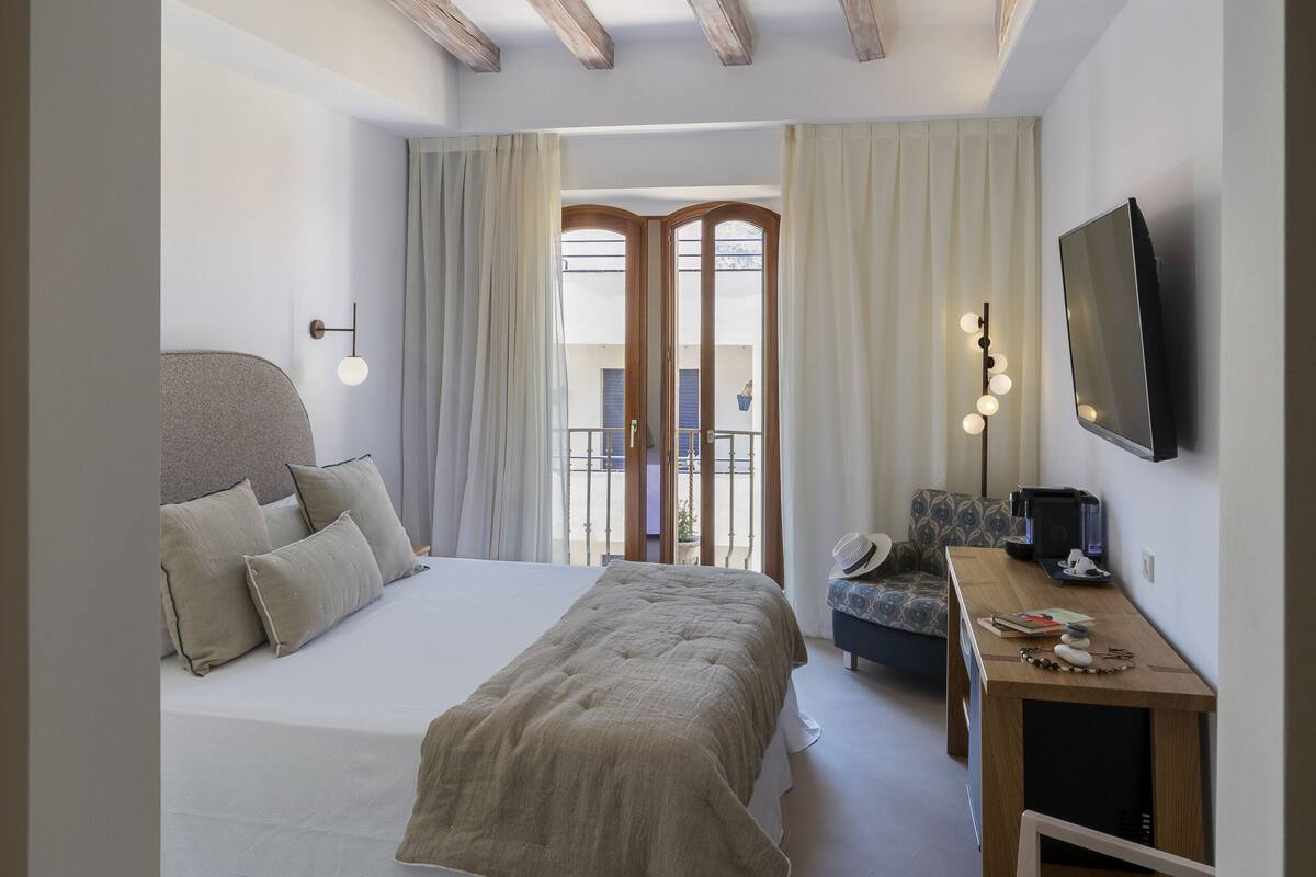 Une chambre à coucher avec un grand lit, un bureau, une chaise et un téléviseur.