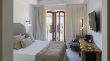 Een slaapkamer met een groot bed, een bureau, een stoel en een televisie.