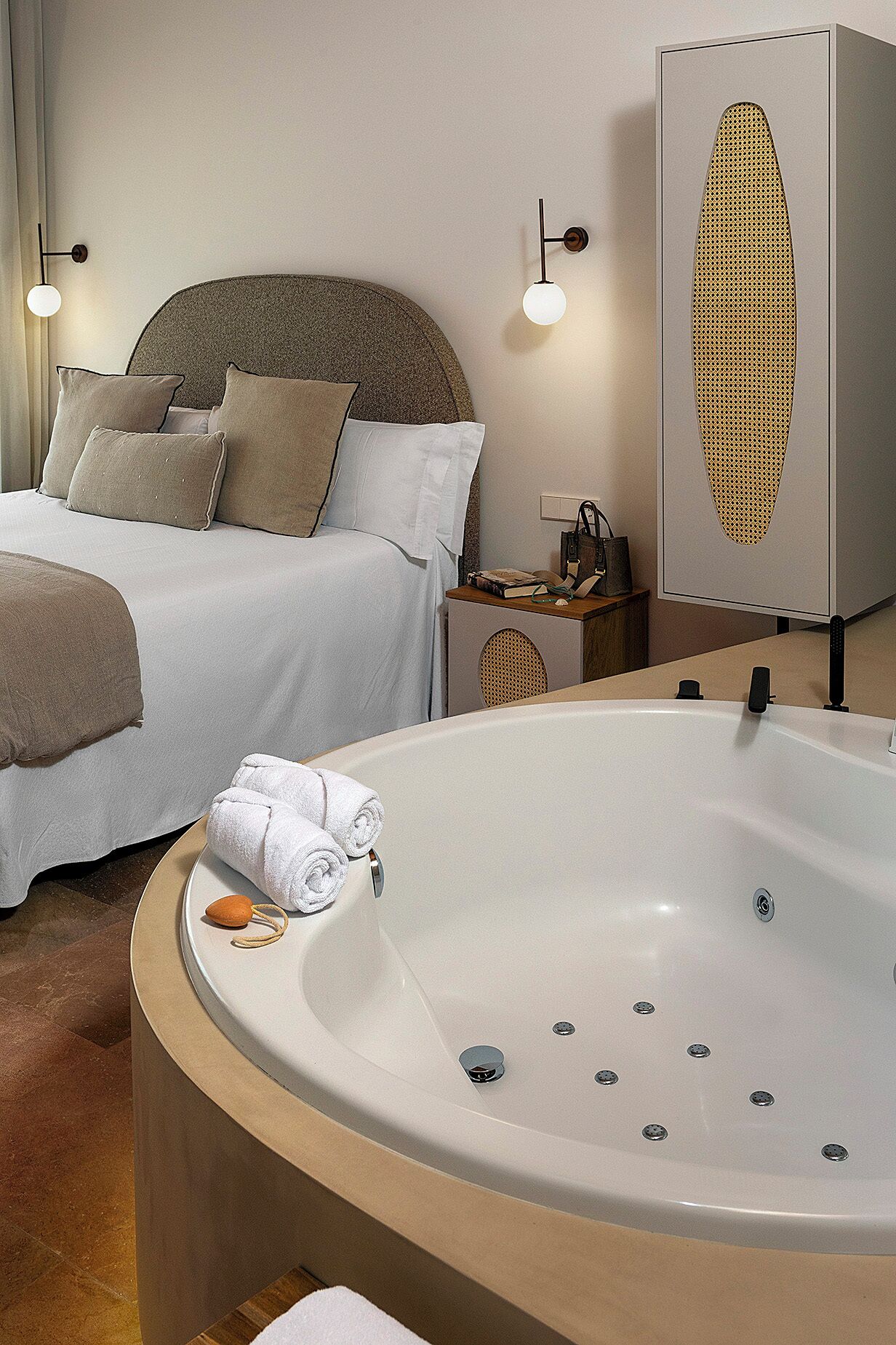 Habitación de hotel con una cama grande, una zona de estar con una silla, una mesita y una bañera amplia.