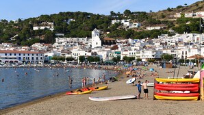 Une ville côtière dotée d’une plage de sable, de bateaux et d’une église située sur une colline.