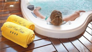 Un bain à remous doté d’une cascade, entouré d’une terrasse en bois et agrémenté de plantes en pot.