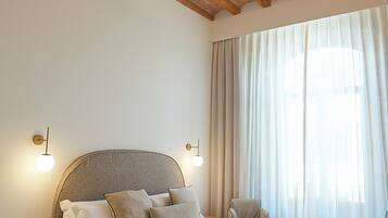 Un dormitorio con una cama grande, vigas de madera en el techo, una mesita de noche con un teléfono y una silla.