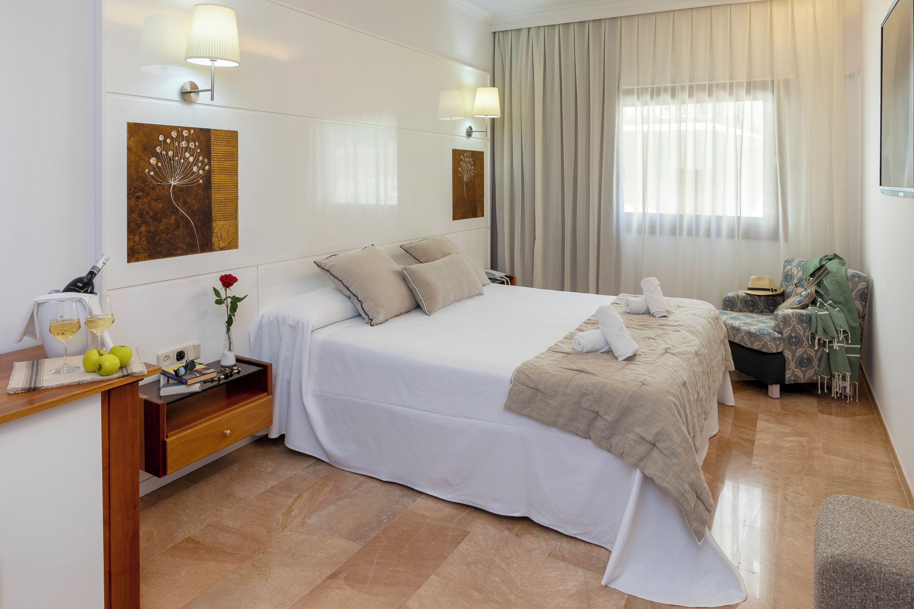 A hotel room with a large bed, bedside tables, a desk, and a chair.