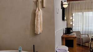 Une salle de bain moderne dotée d’une grande baignoire, d’un meuble-lavabo en bois et d’un coin salon avec une chaise et une table.