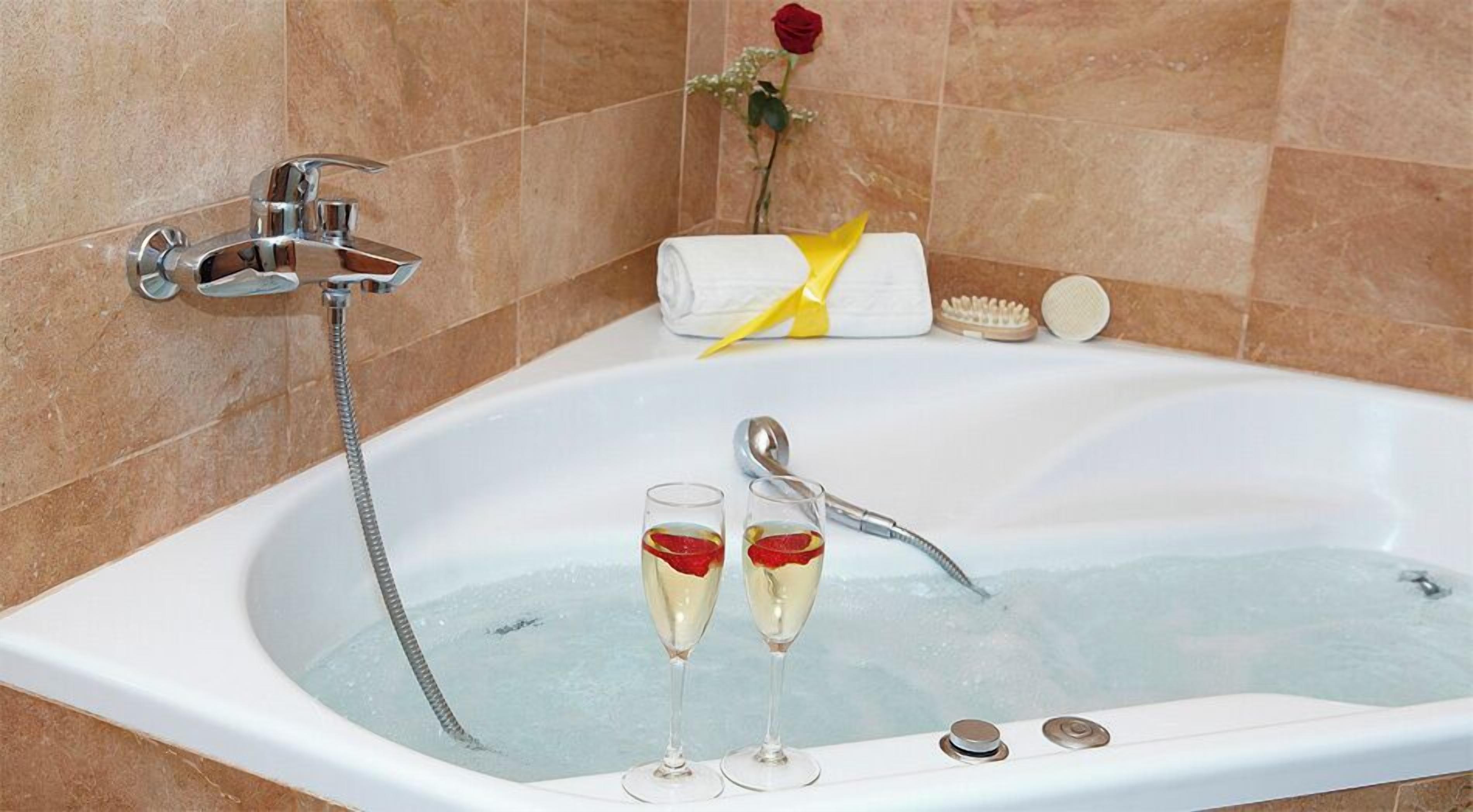 Une baignoire, deux coupes de champagne, une rose et une serviette.
