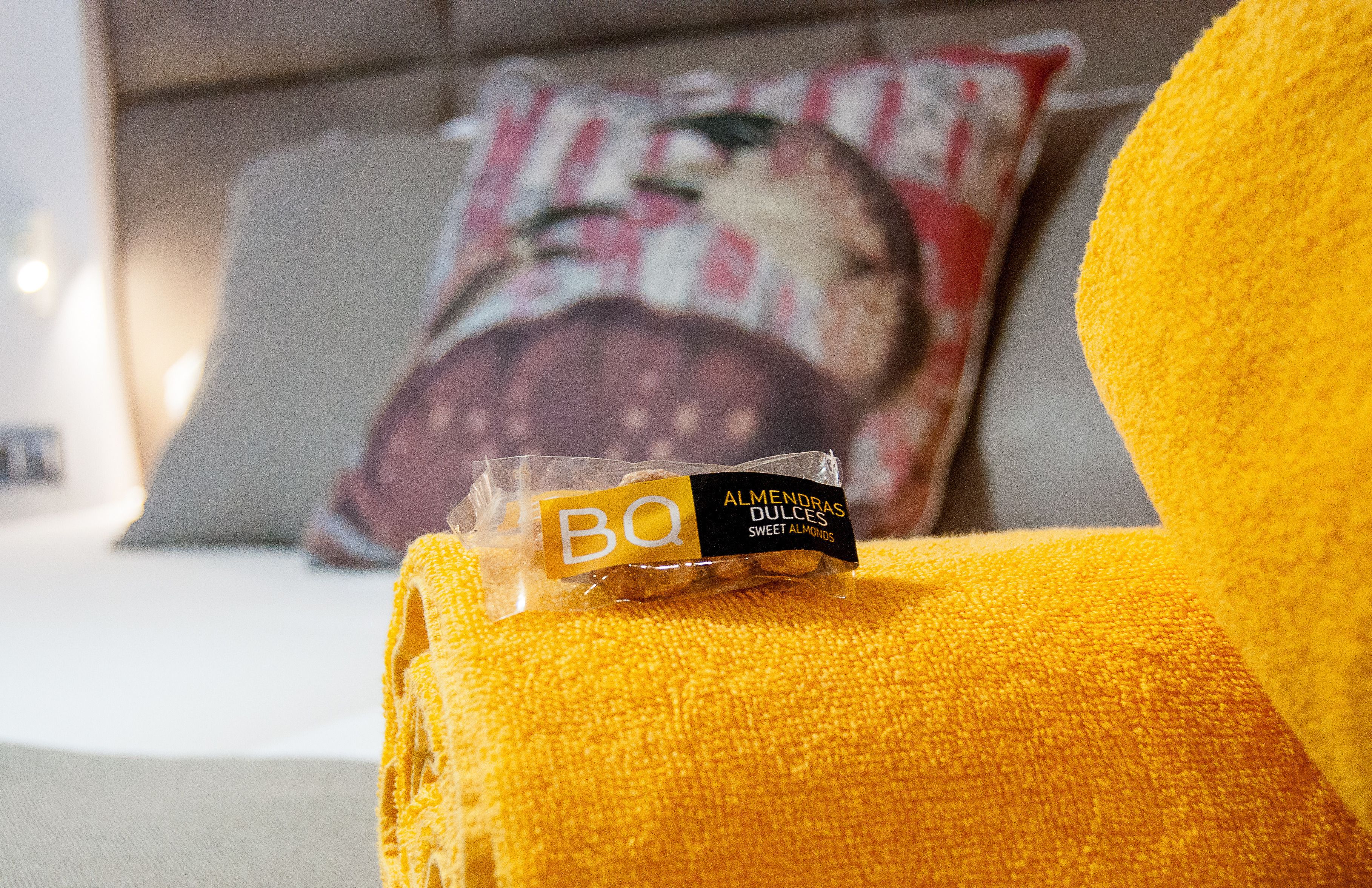 A package of BQ sweet almonds on a yellow cushion.
