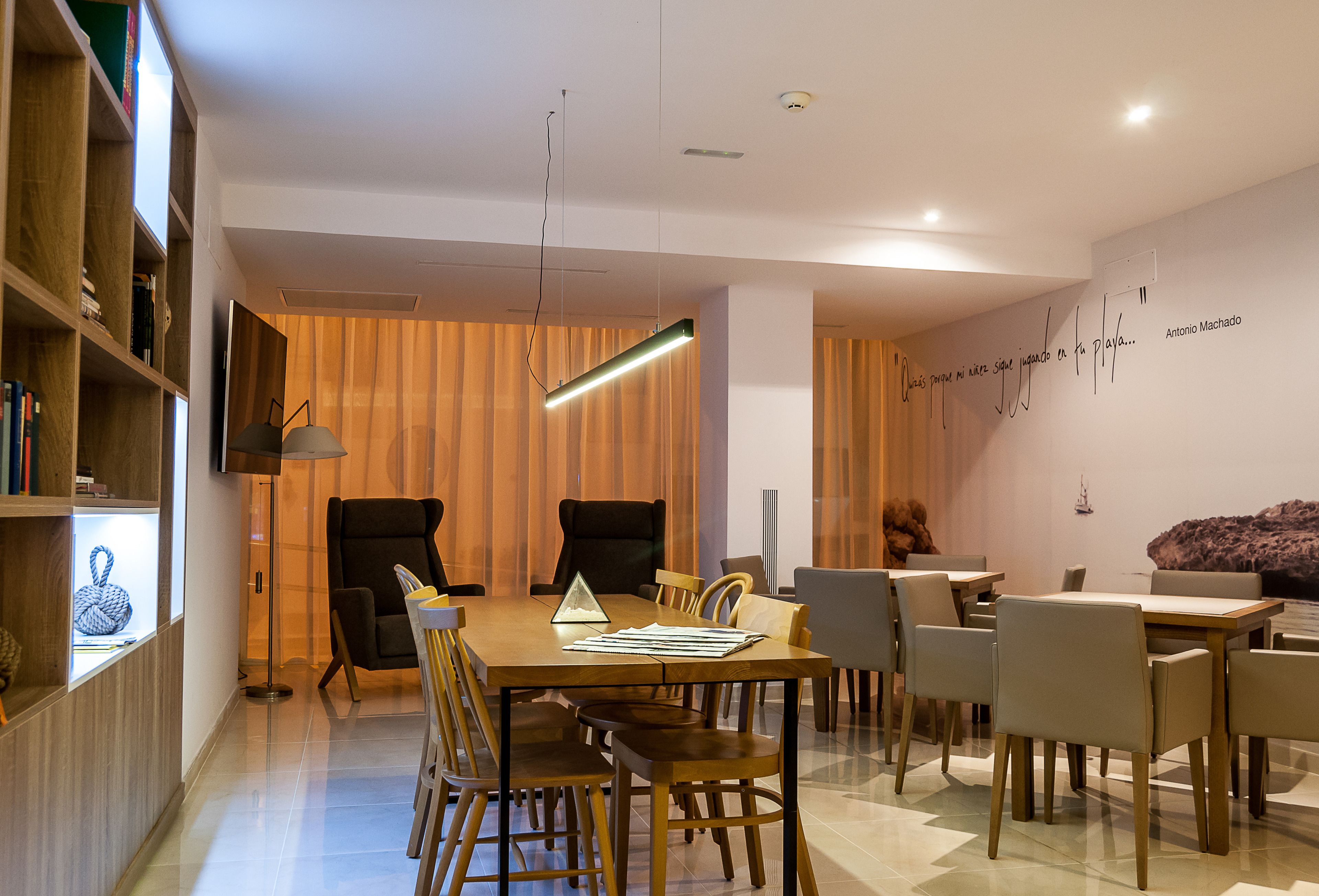 Un espace de salle à manger moderne avec une table en bois, des chaises et un luminaire suspendu.