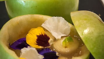 A dessert in a green bowl with a flower and a yellow fruit slice.