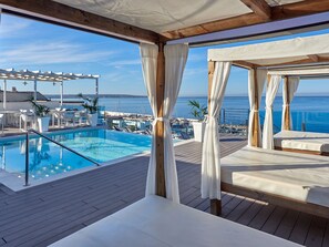 A poolside area with a wooden deck, lounge chairs, and a view of the sea. - BQ Aguamarina Boutique Hotel (Palma de Mallorca)