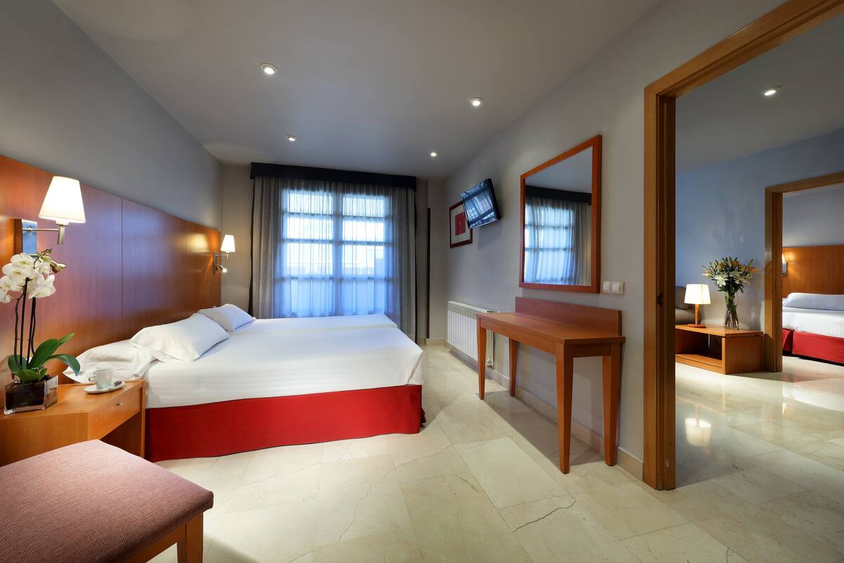 Una habitación de hotel con una cama grande, un escritorio de madera, un televisor y un espejo de baño.
