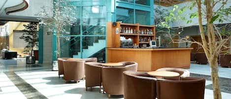 Un vestíbulo moderno con zona de bar, asientos y una escalera.