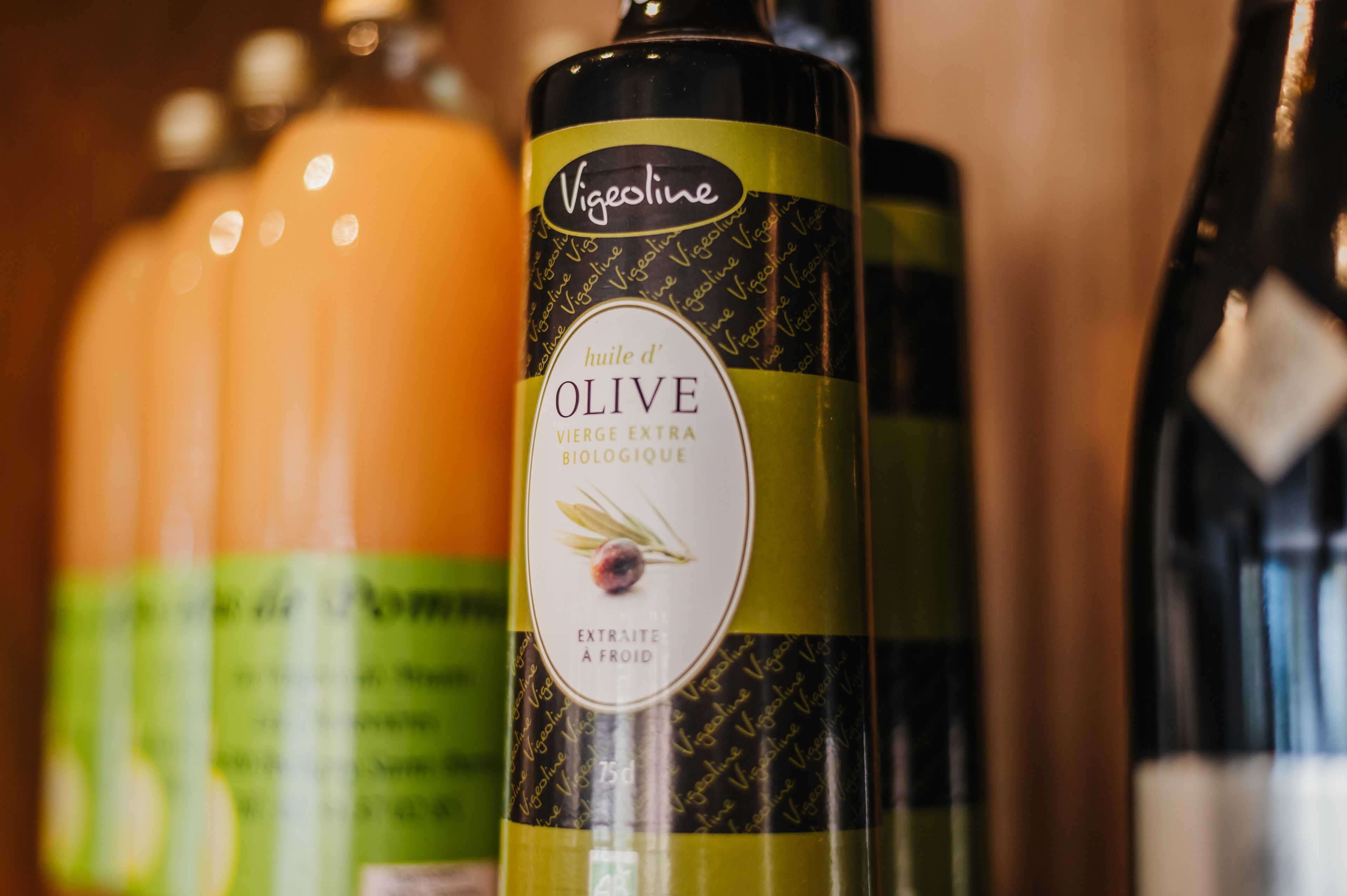A close-up of a bottle with a label that reads "huile d'OLIVE VIERGE EXTRA BIOLOGIQUE EXTRAITE A FROID."